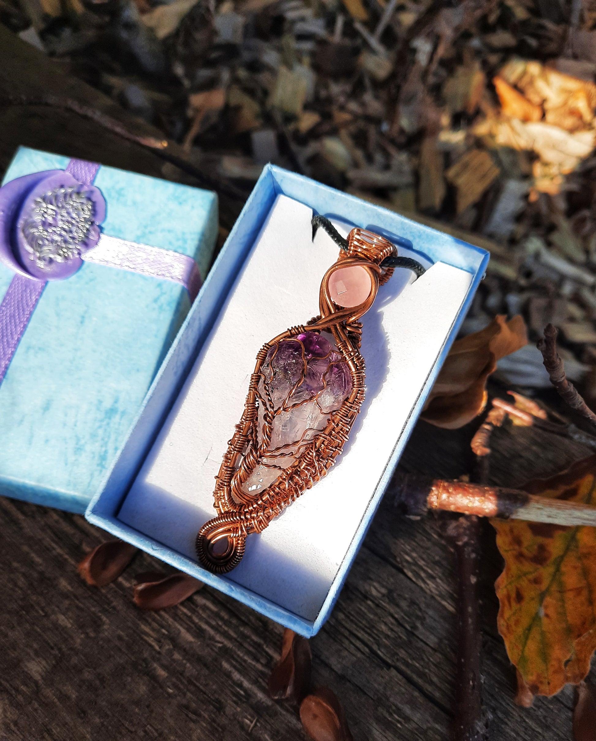 Amethyst and rose quartz tree of life pendant. Copper wire, weaved framed with swirls. Gift boxed. Autumn background.